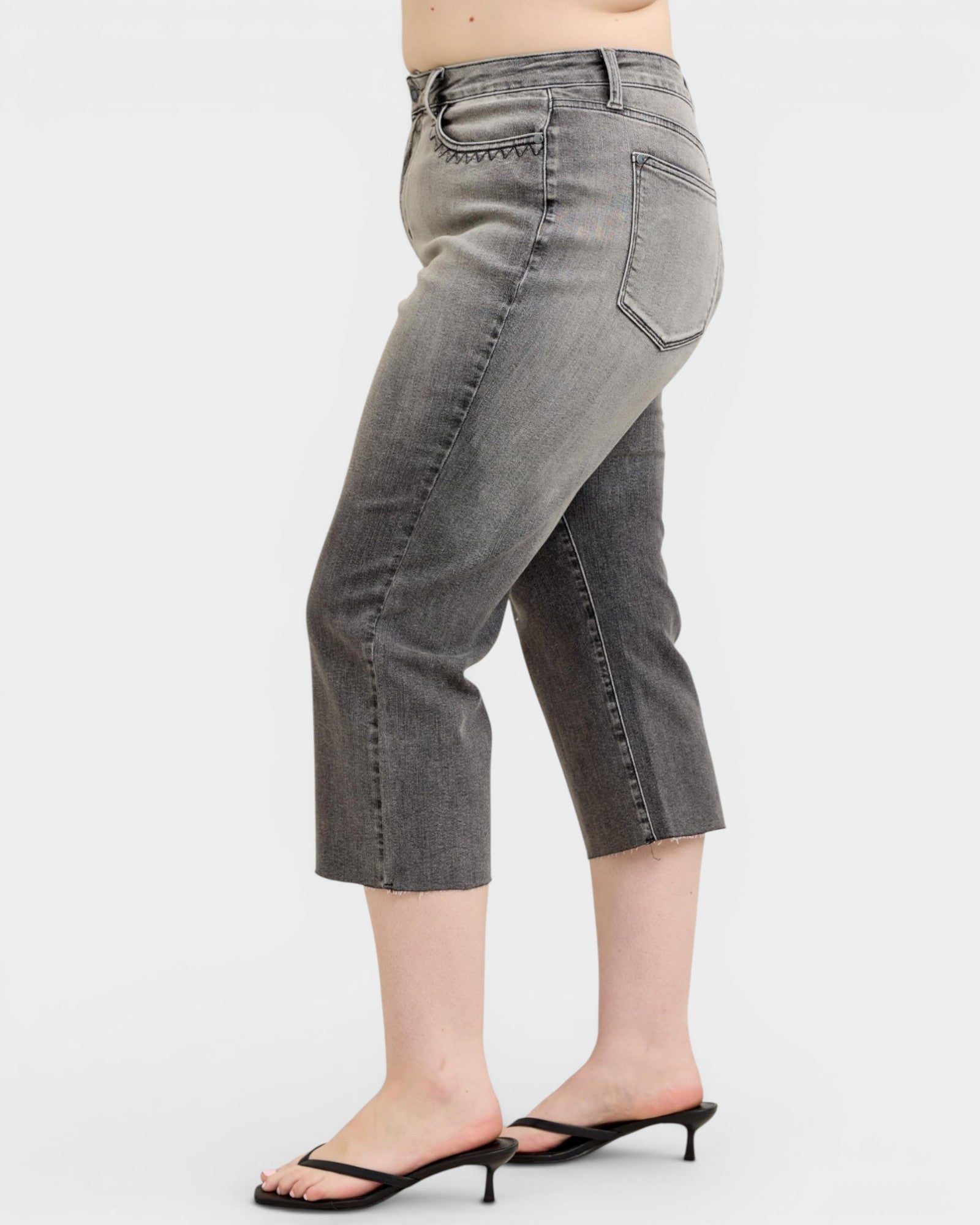 Person wearing gray cropped jeans on a white background