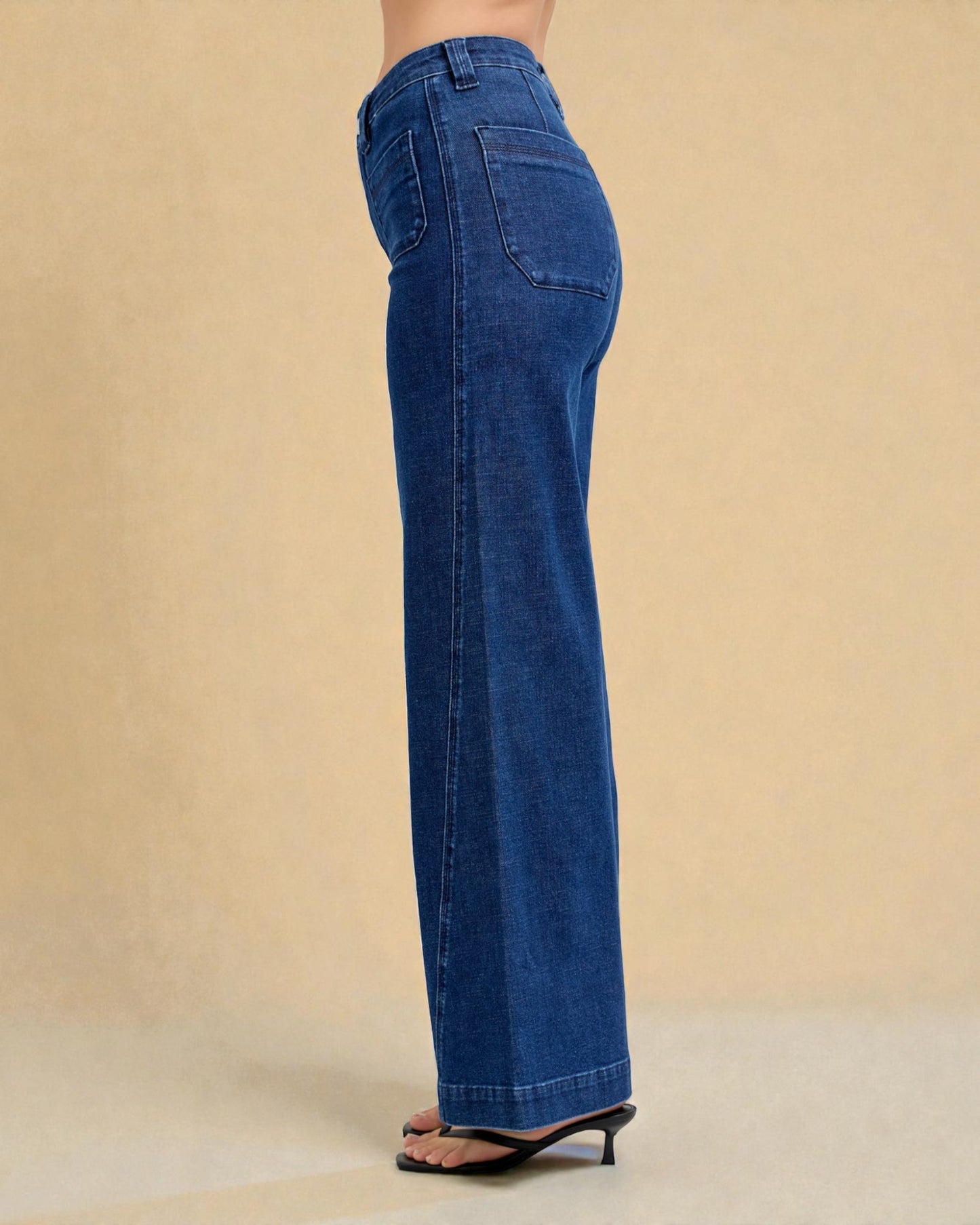 Blue jeans worn by a person on a beige background