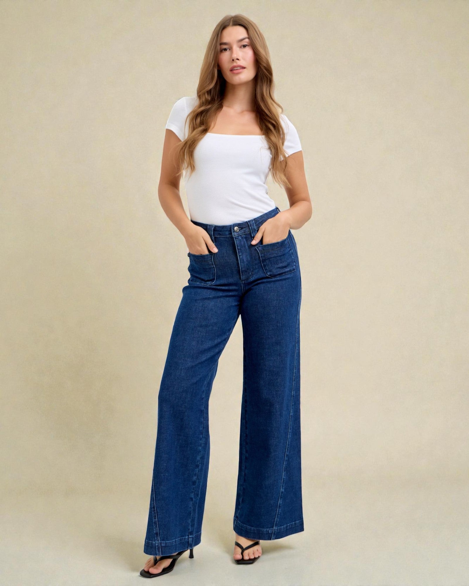 Woman wearing blue jeans and a white top on a beige background