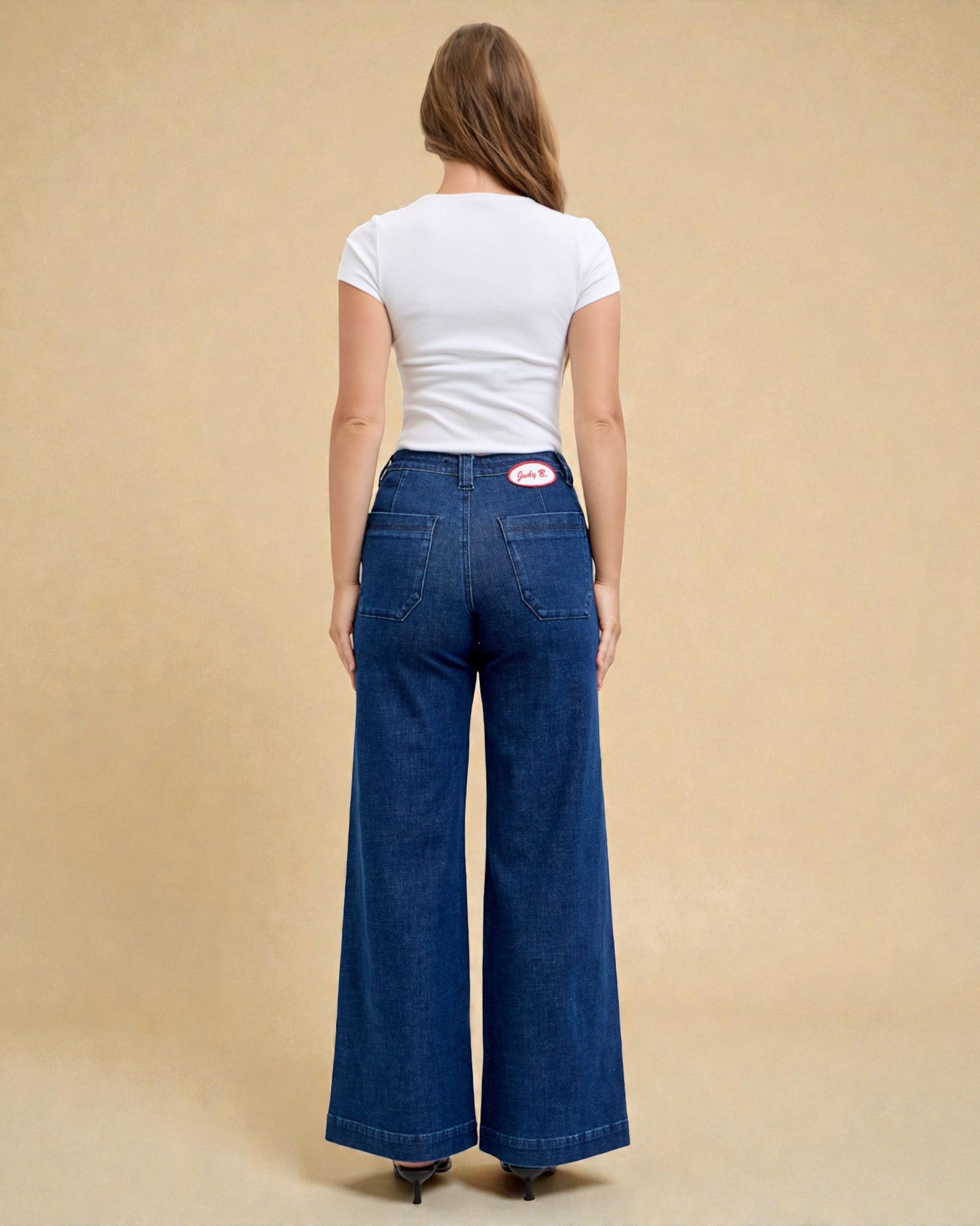 Woman wearing blue jeans and a white t-shirt on a beige background