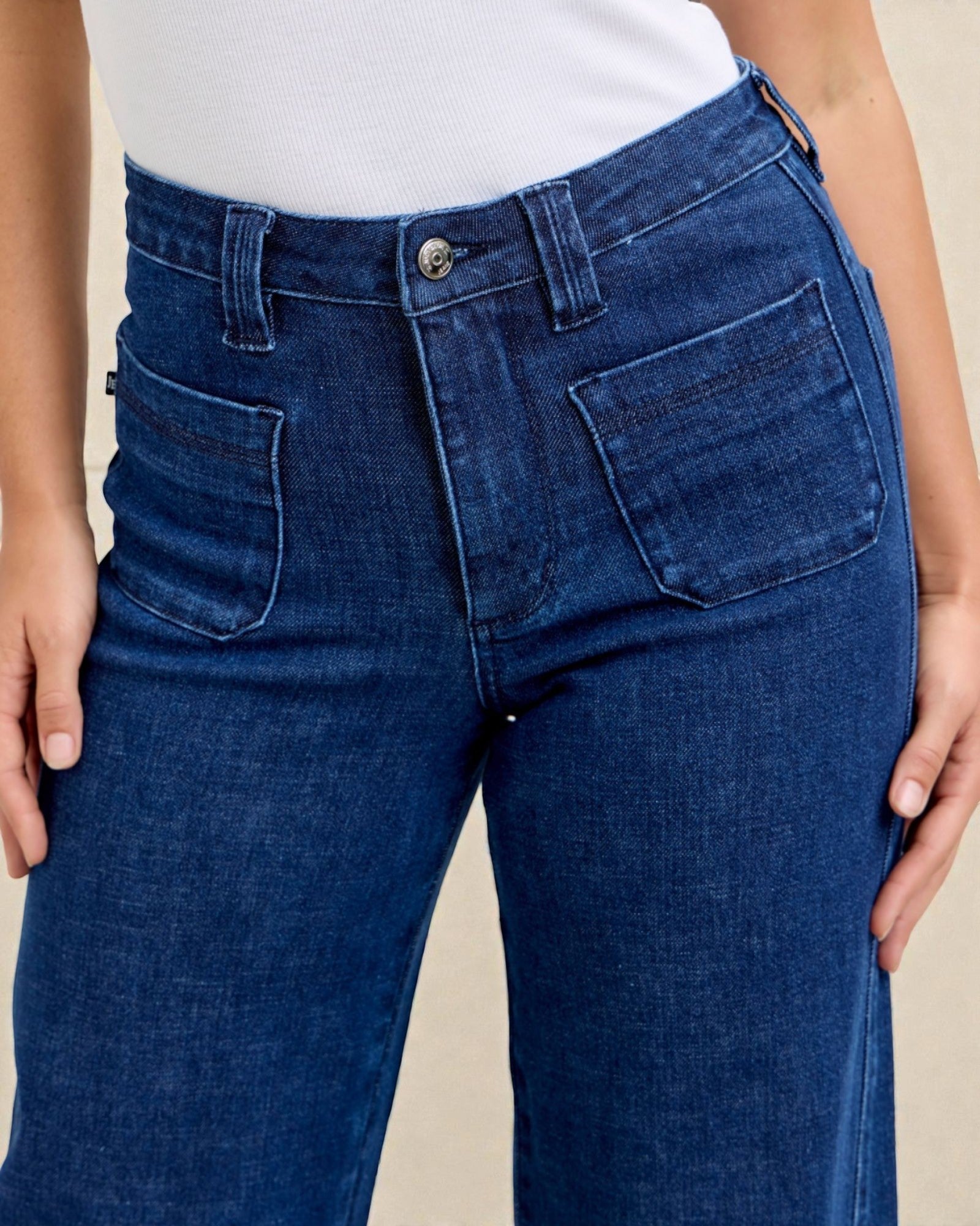 Blue jeans worn by a person on a beige background