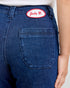 Blue jeans with a red and white patch on the back pocket against a white background