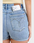 Person wearing blue denim shorts with a phone in the back pocket on a plain background