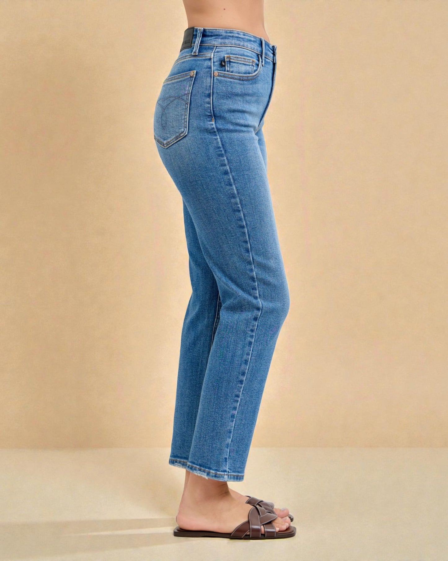 Blue jeans worn by a person on a beige background