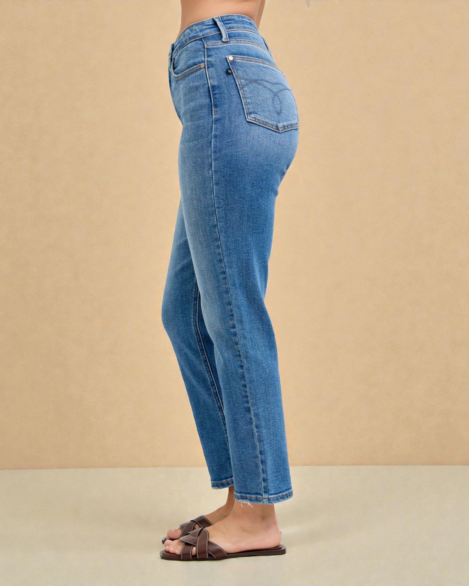 Blue jeans worn by a person on a beige background