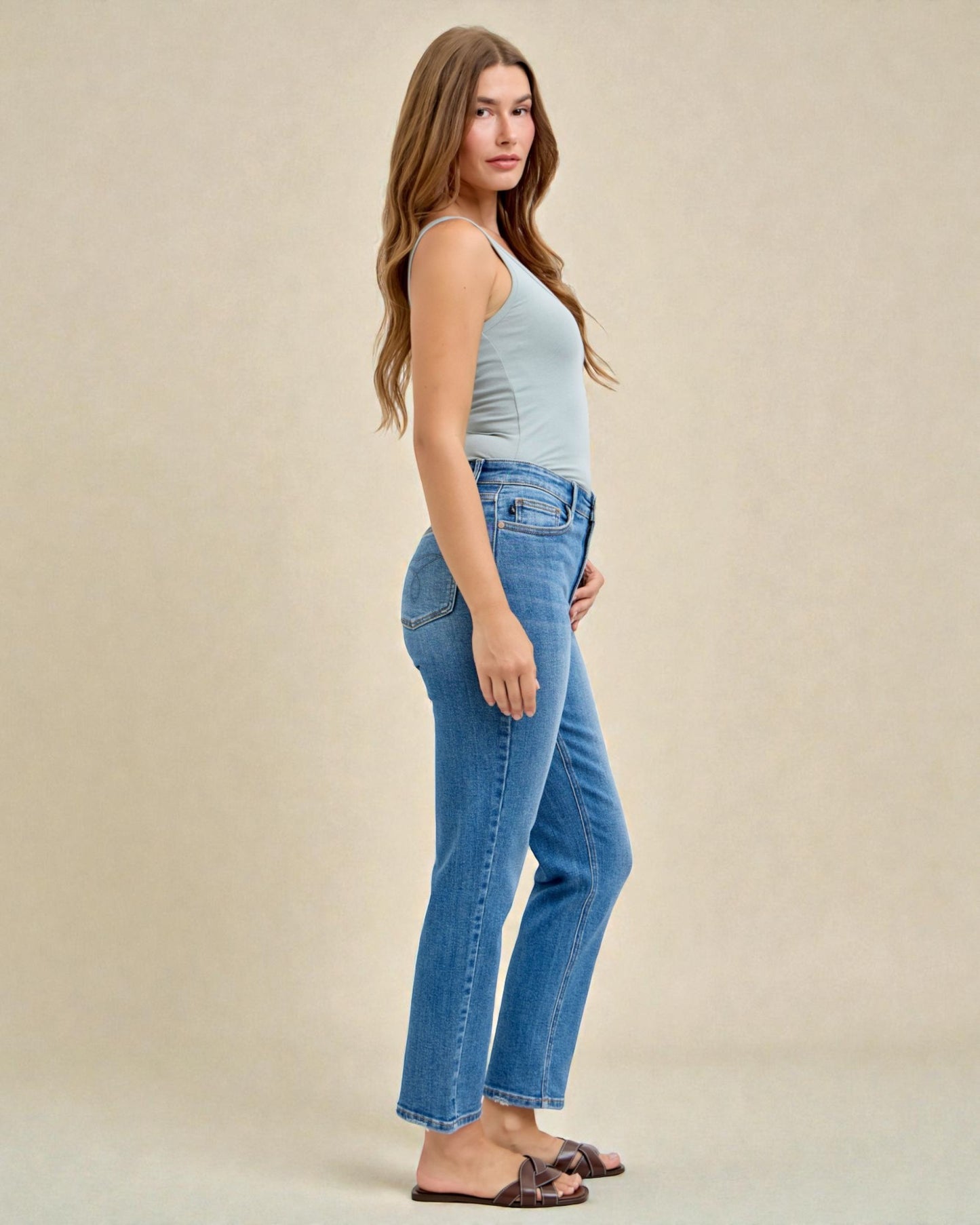 Woman wearing blue jeans and a light blue top on a beige background