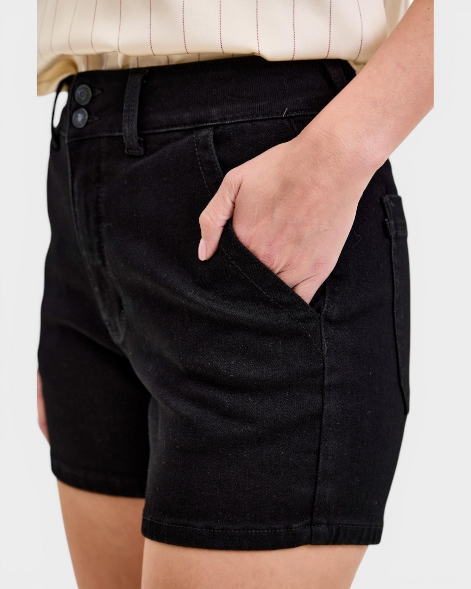 Person wearing black shorts with a plain background