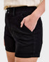 Person wearing black shorts with a plain background