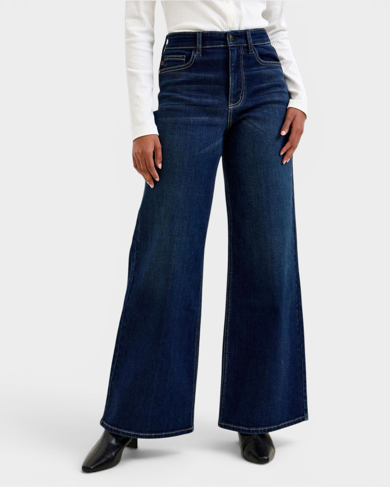 Person wearing dark blue wide-leg jeans on a white background