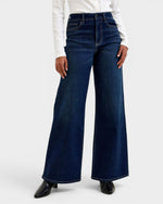 Person wearing dark blue wide-leg jeans on a white background