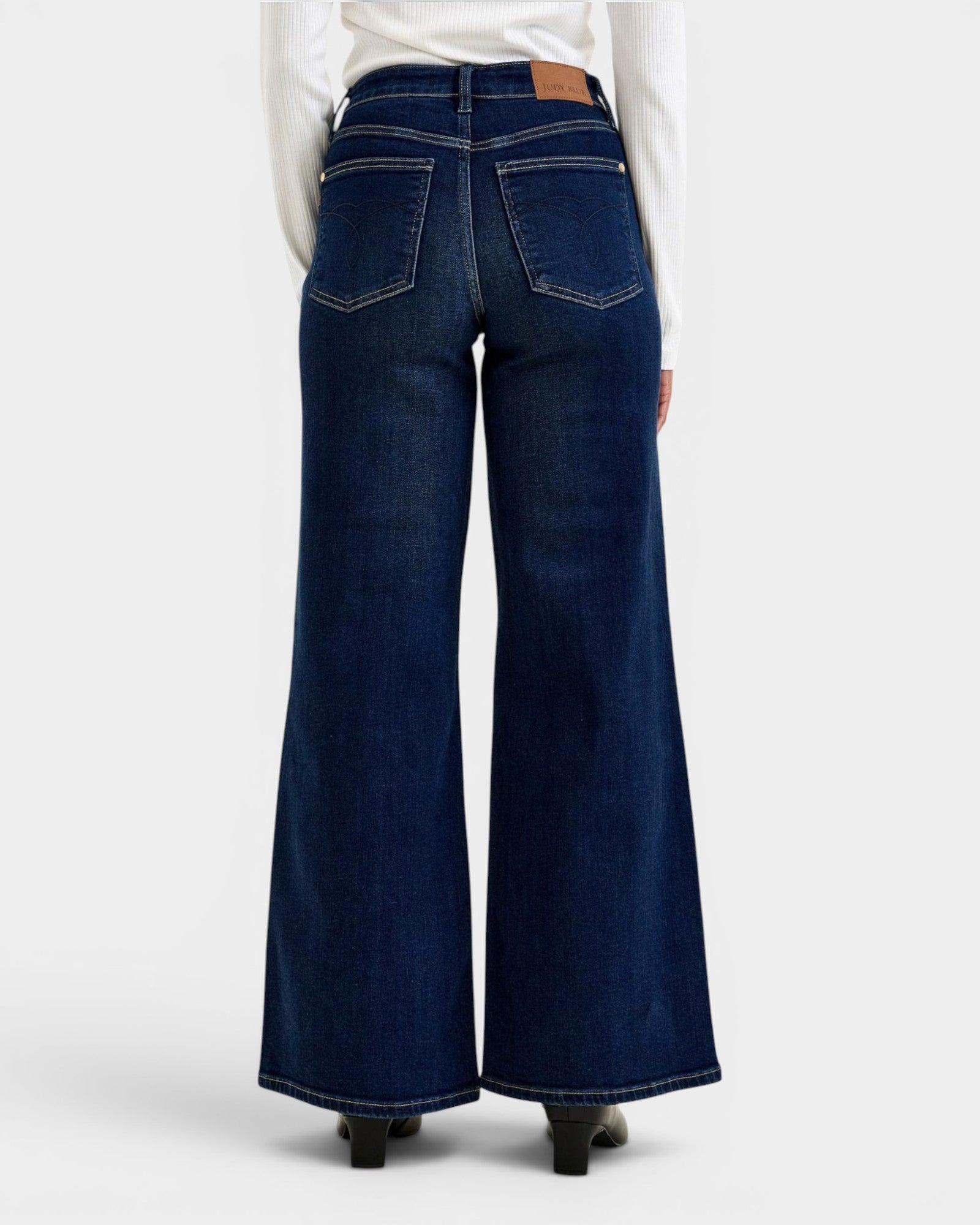 Dark blue wide-leg jeans worn by a person on a white background