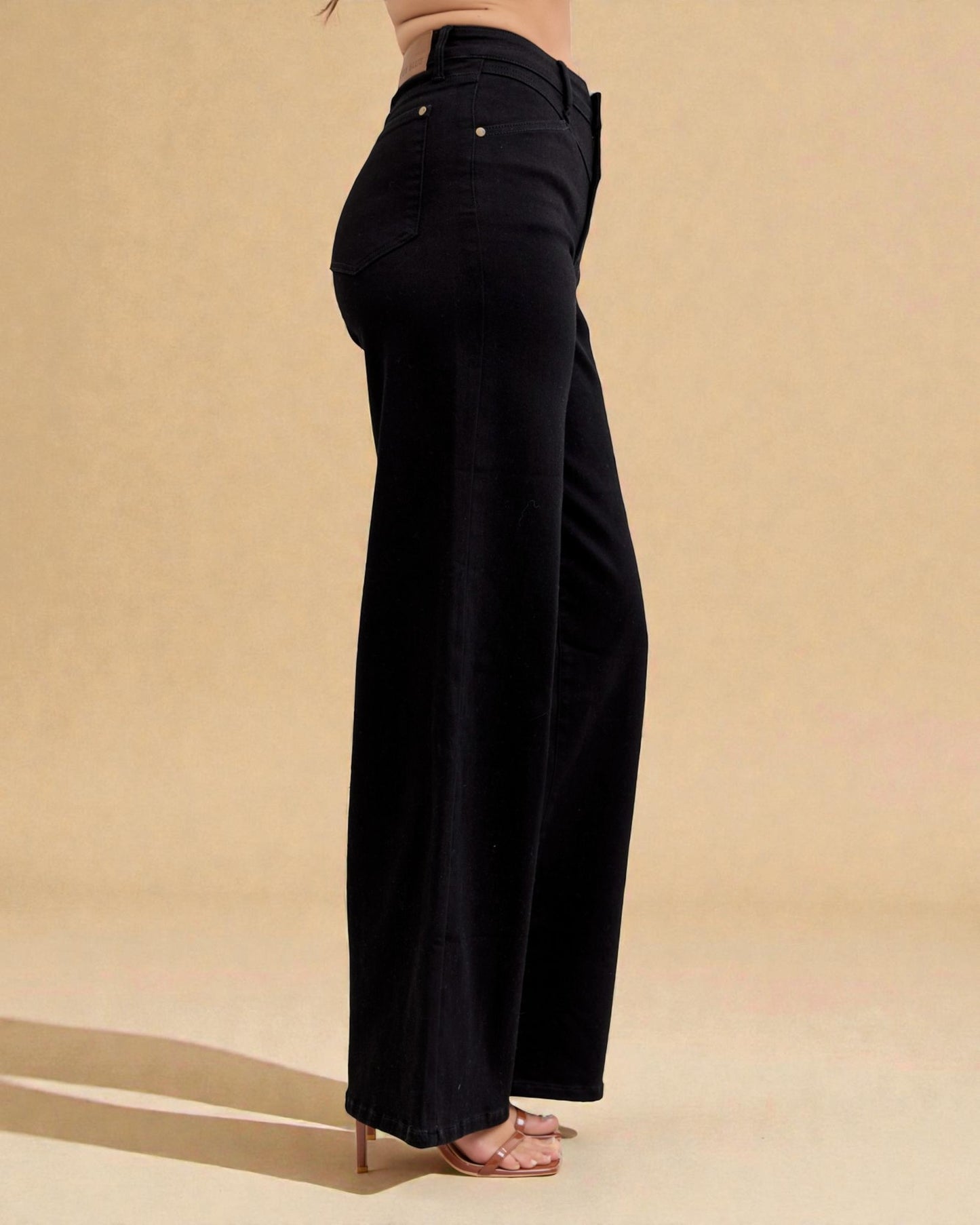 Black wide-leg pants worn by a person on a beige background