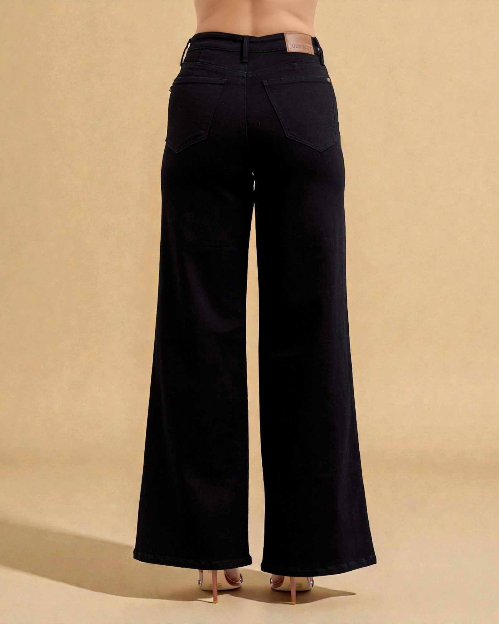 Black wide-leg jeans on a beige background