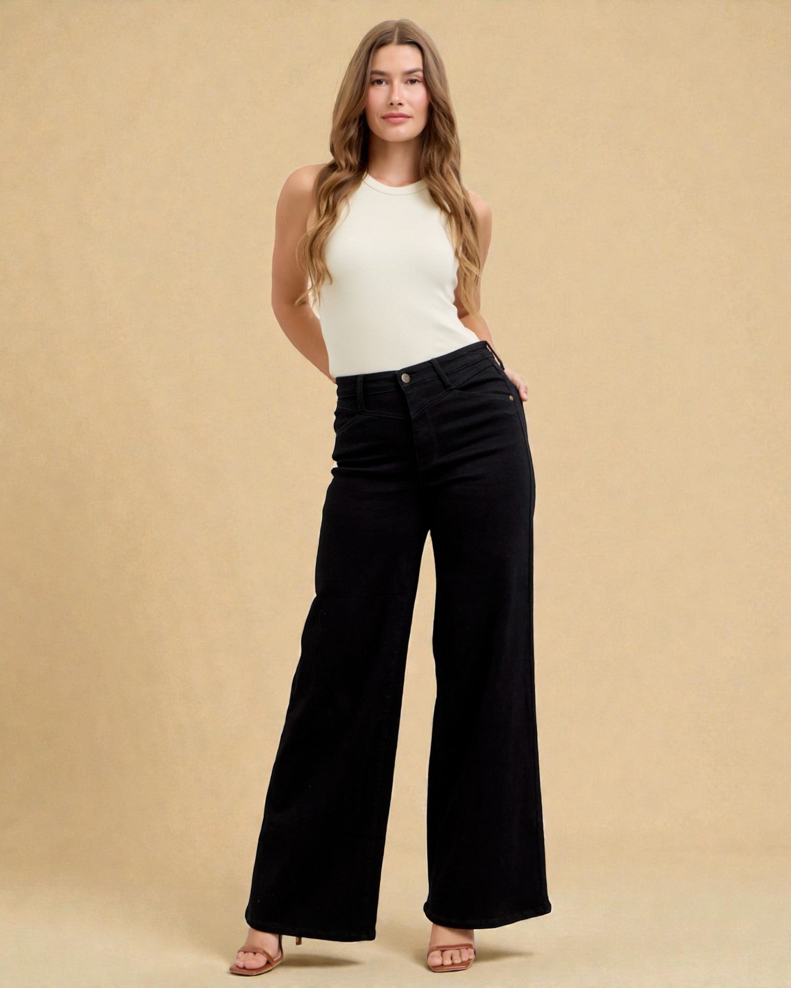 Woman wearing a white top and black flared pants against a beige background