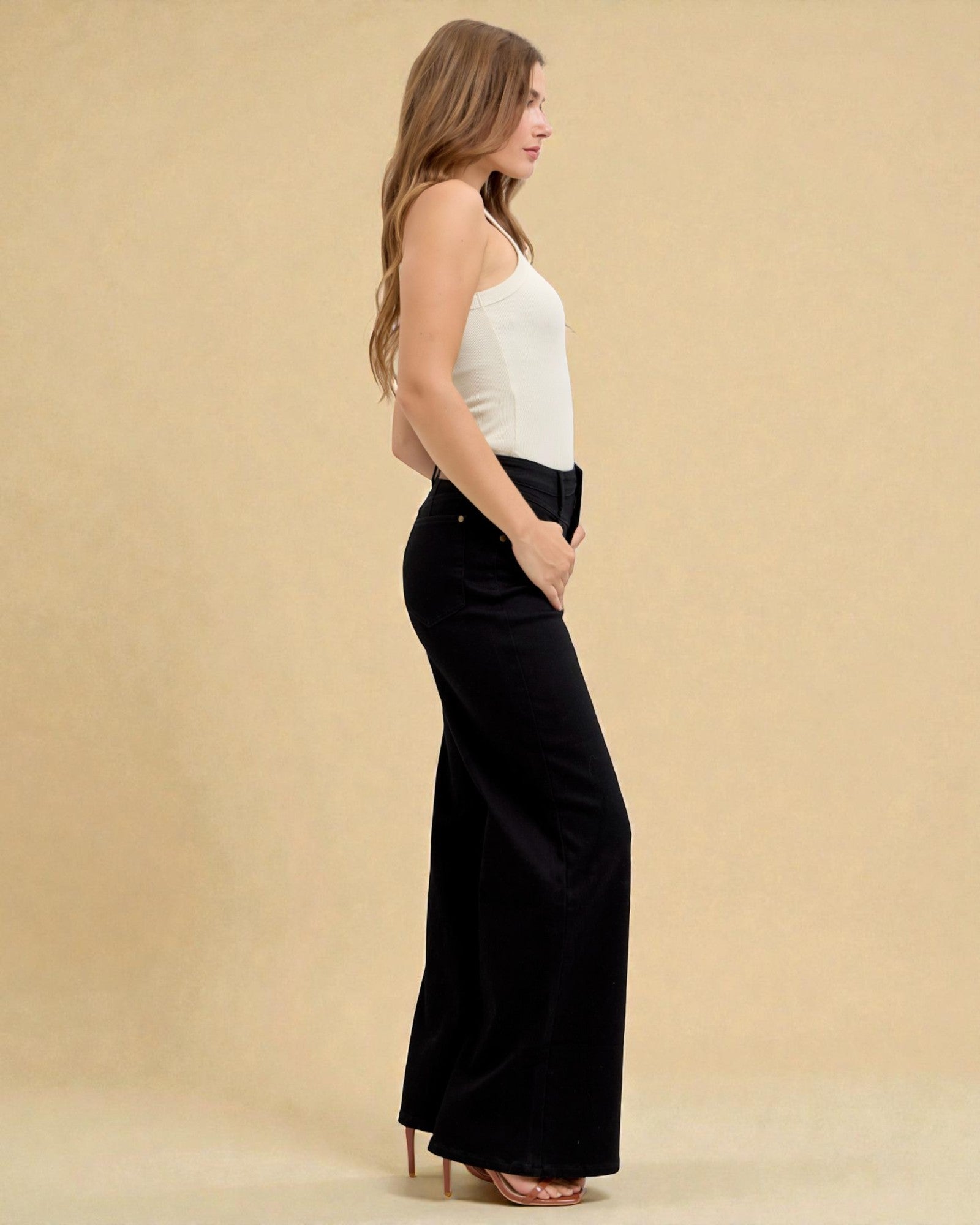 Woman wearing a white top and black wide-leg pants on a beige background