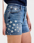 Blue denim shorts with white star pattern worn by a person on a plain background