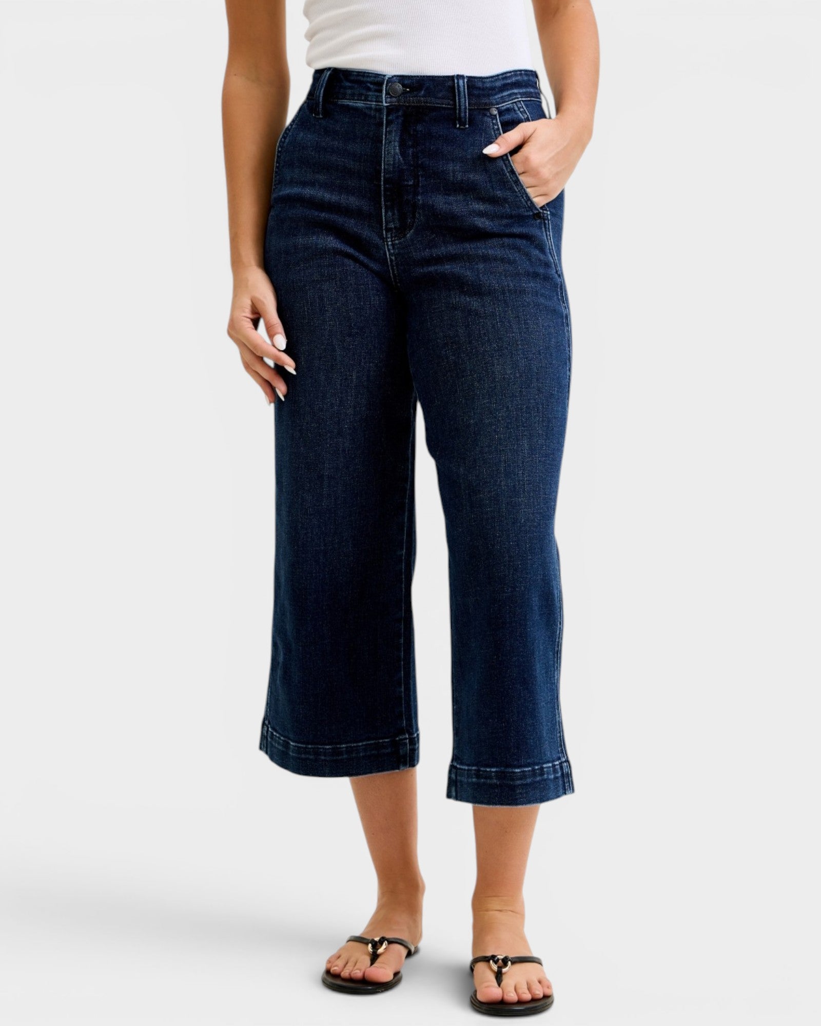 Person wearing dark blue jeans on a white background