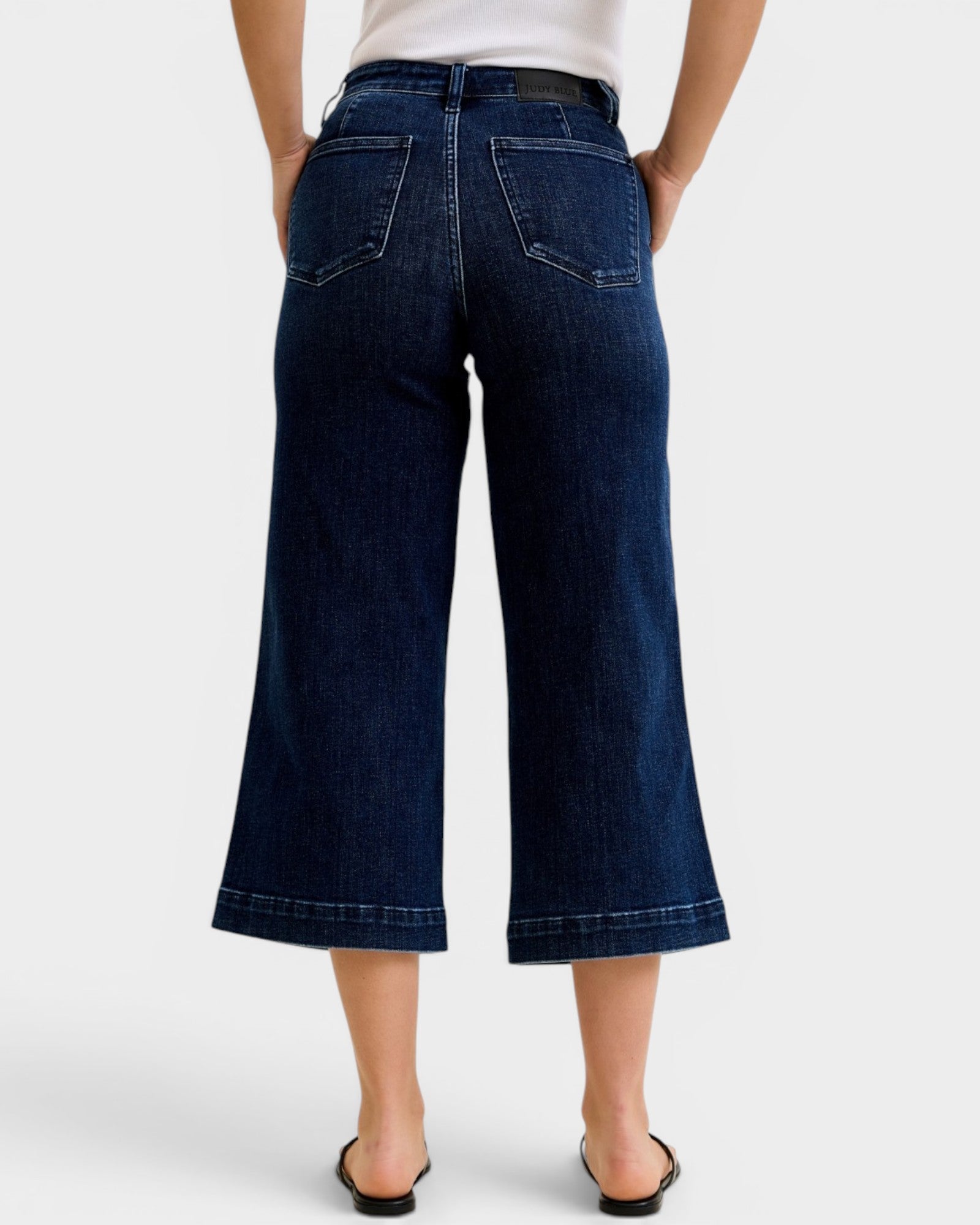 Person wearing dark blue wide-leg jeans on a white background