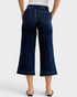 Person wearing dark blue wide-leg jeans on a white background