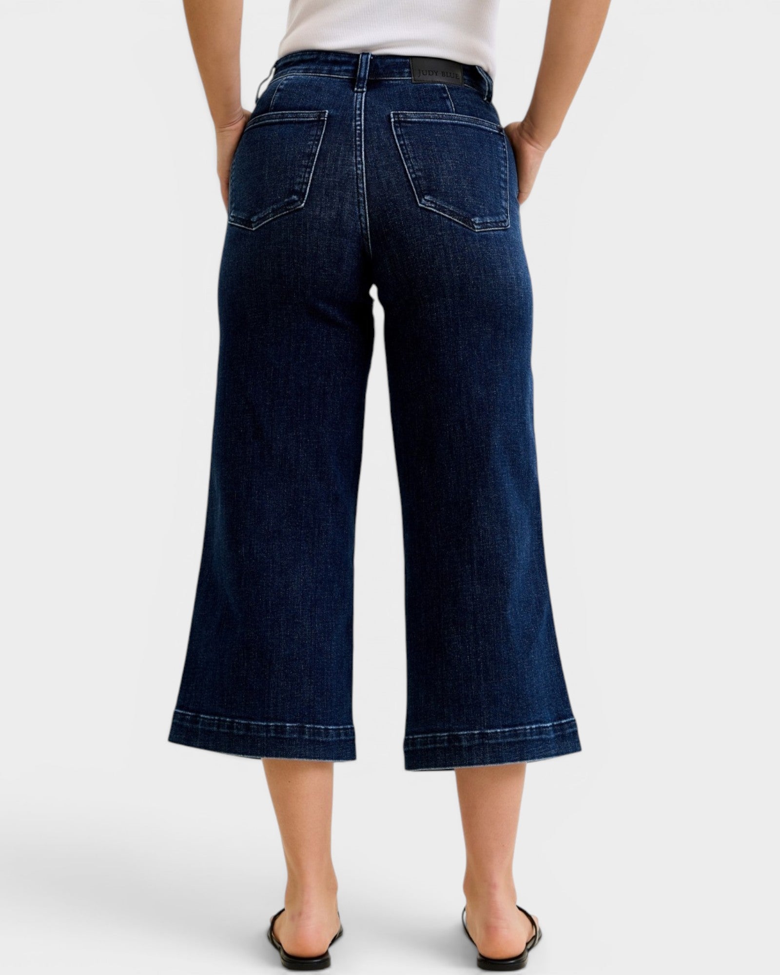 Person wearing dark blue wide-leg jeans on a white background