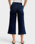 Person wearing dark blue wide-leg jeans on a white background