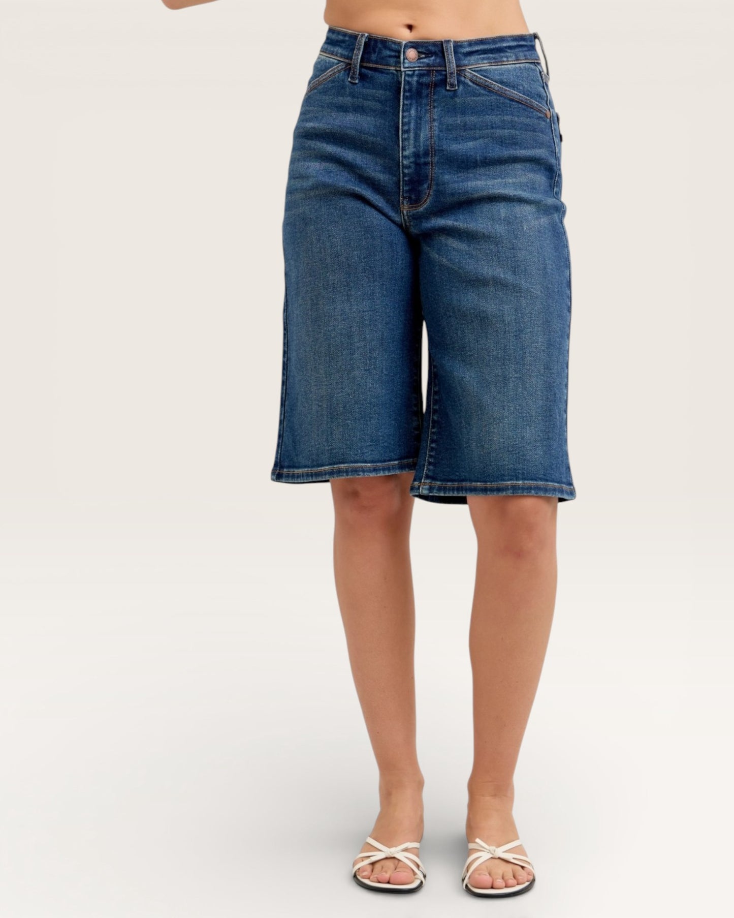 Blue denim shorts worn by a person on a white background