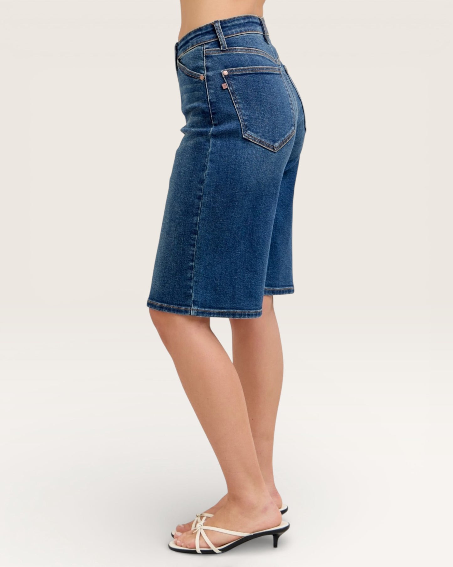 Blue denim shorts worn by a person on a white background