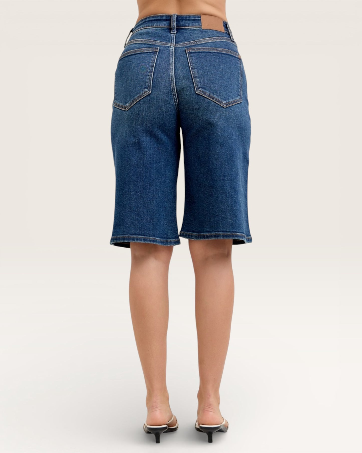Blue denim shorts worn by a person on a white background