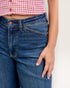 Person wearing blue jeans and a red and white checkered shirt on a light gray background