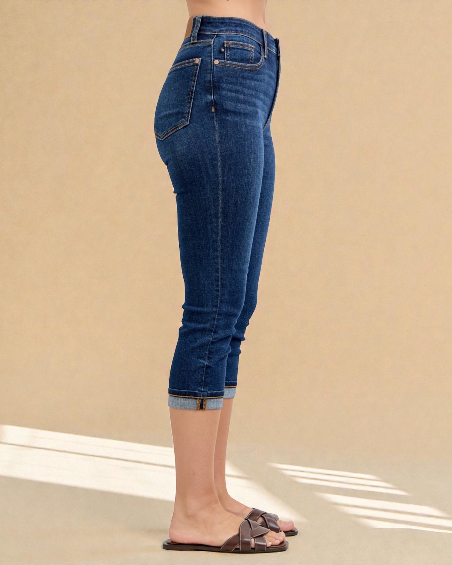 Blue jeans worn by a person on a beige background