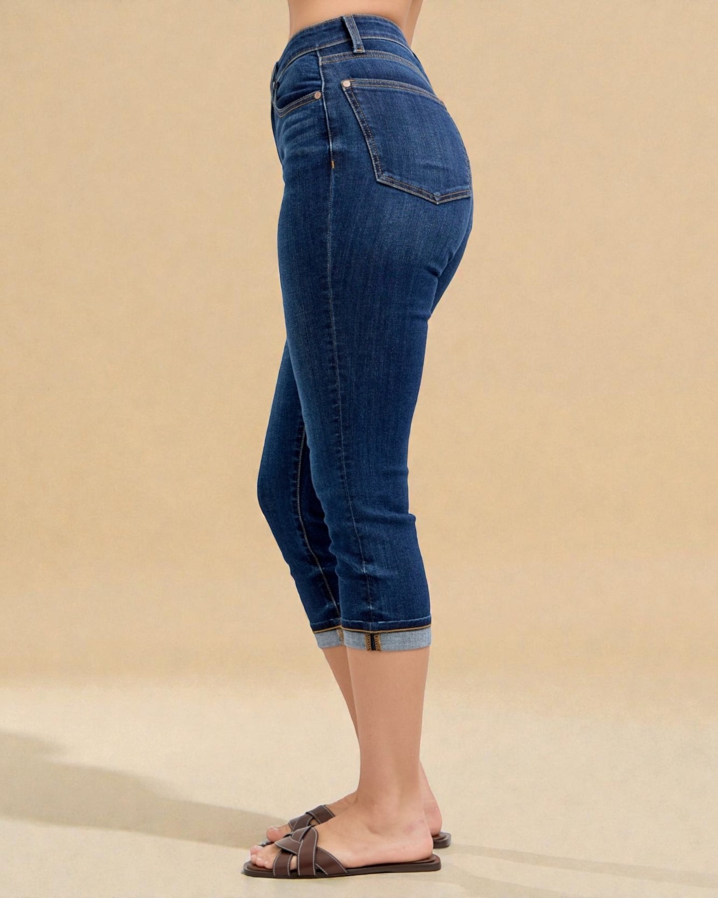 Blue jeans worn by a person on a beige background