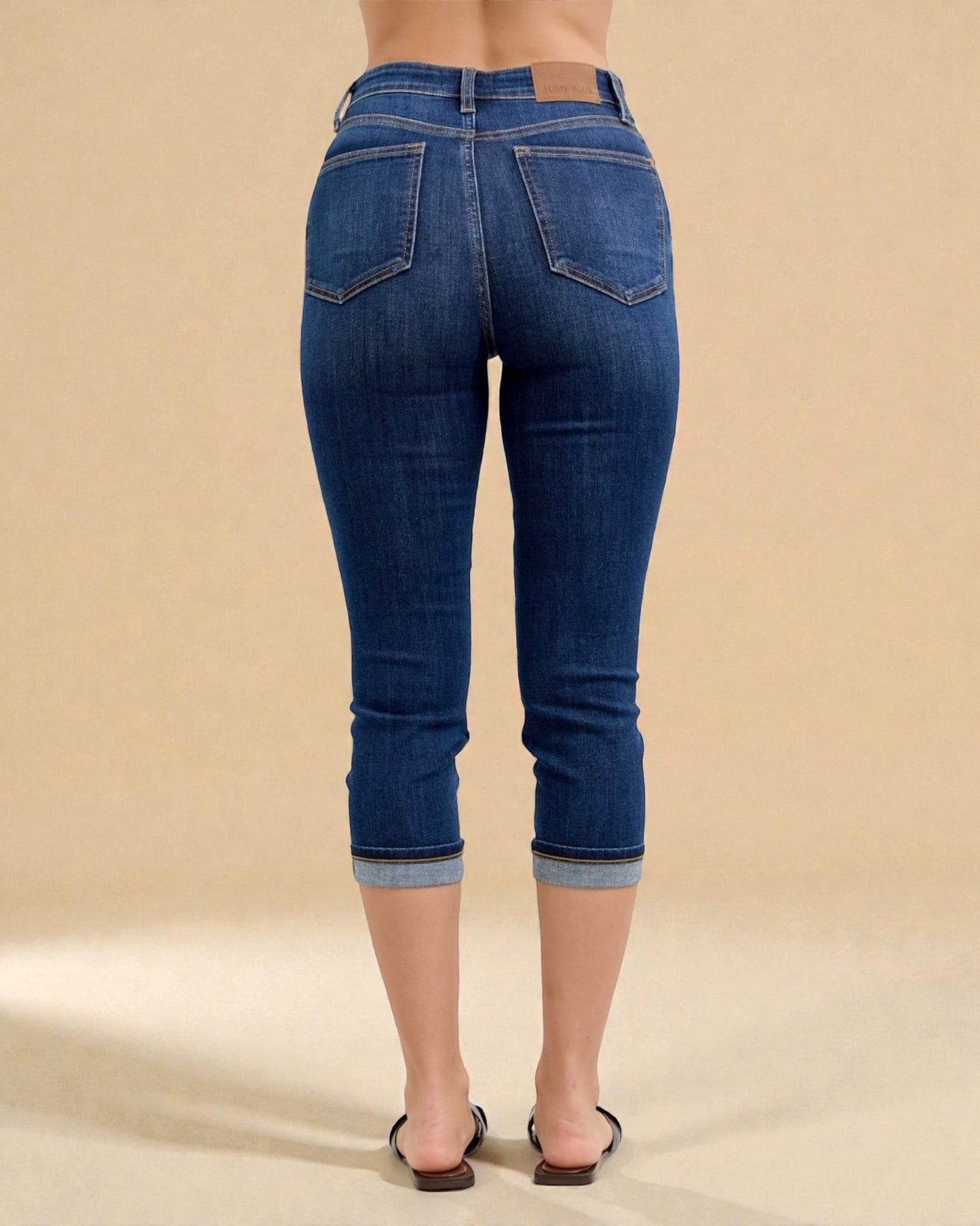 Blue jeans worn by a person on a beige background