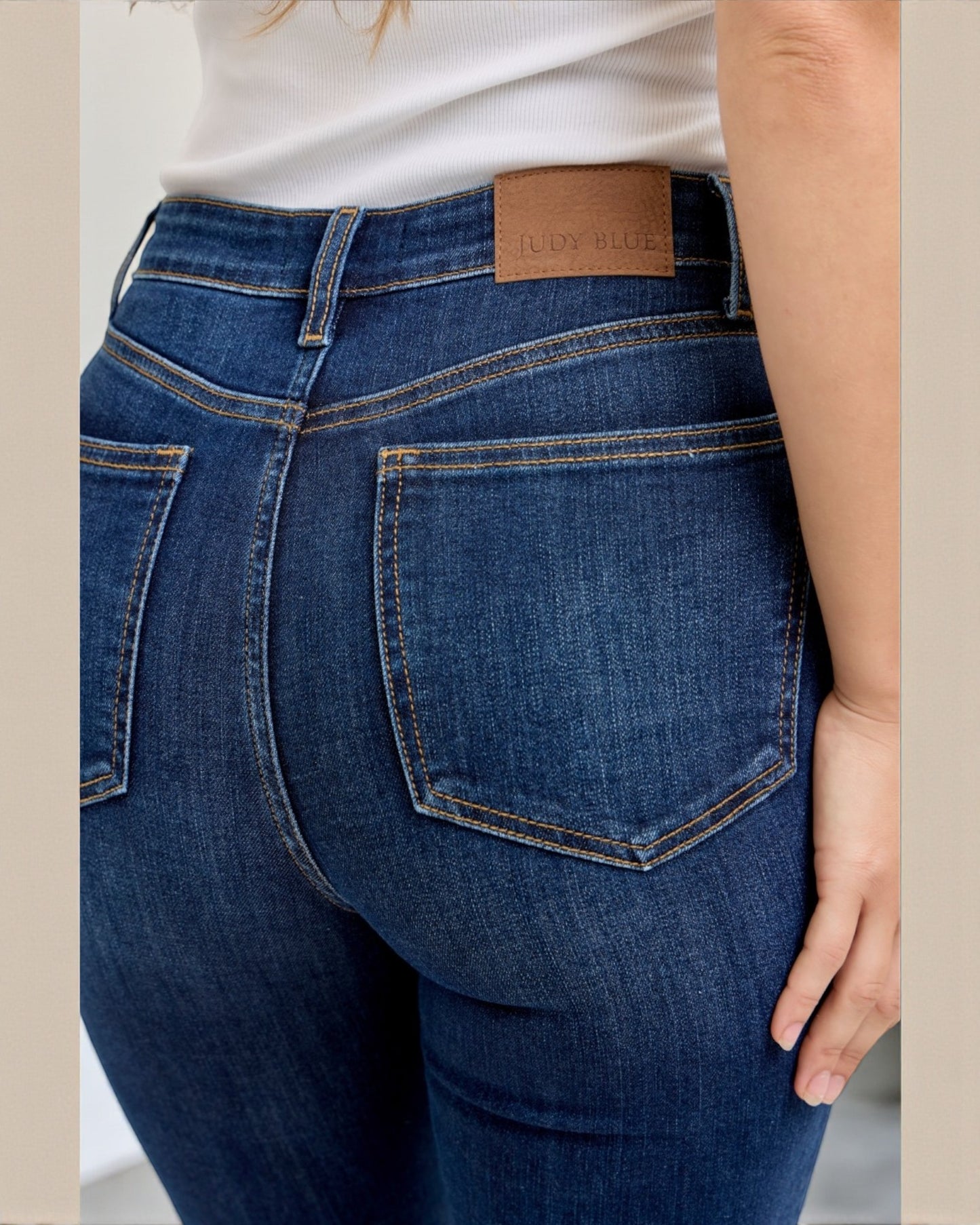 Close-up of blue jeans with a brand label on a neutral background