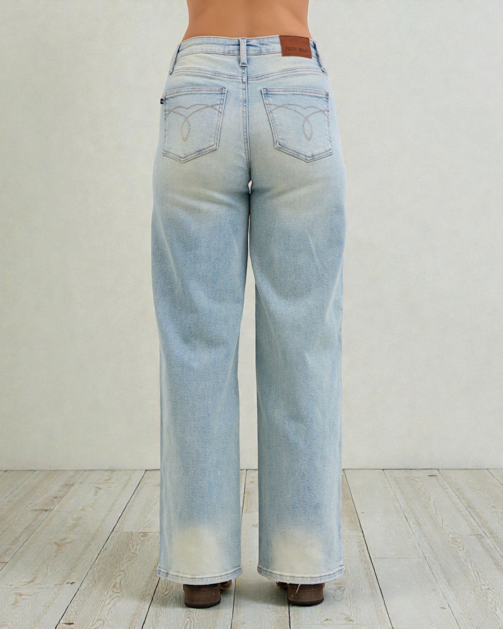 Light blue jeans worn by a person on a white wooden floor.