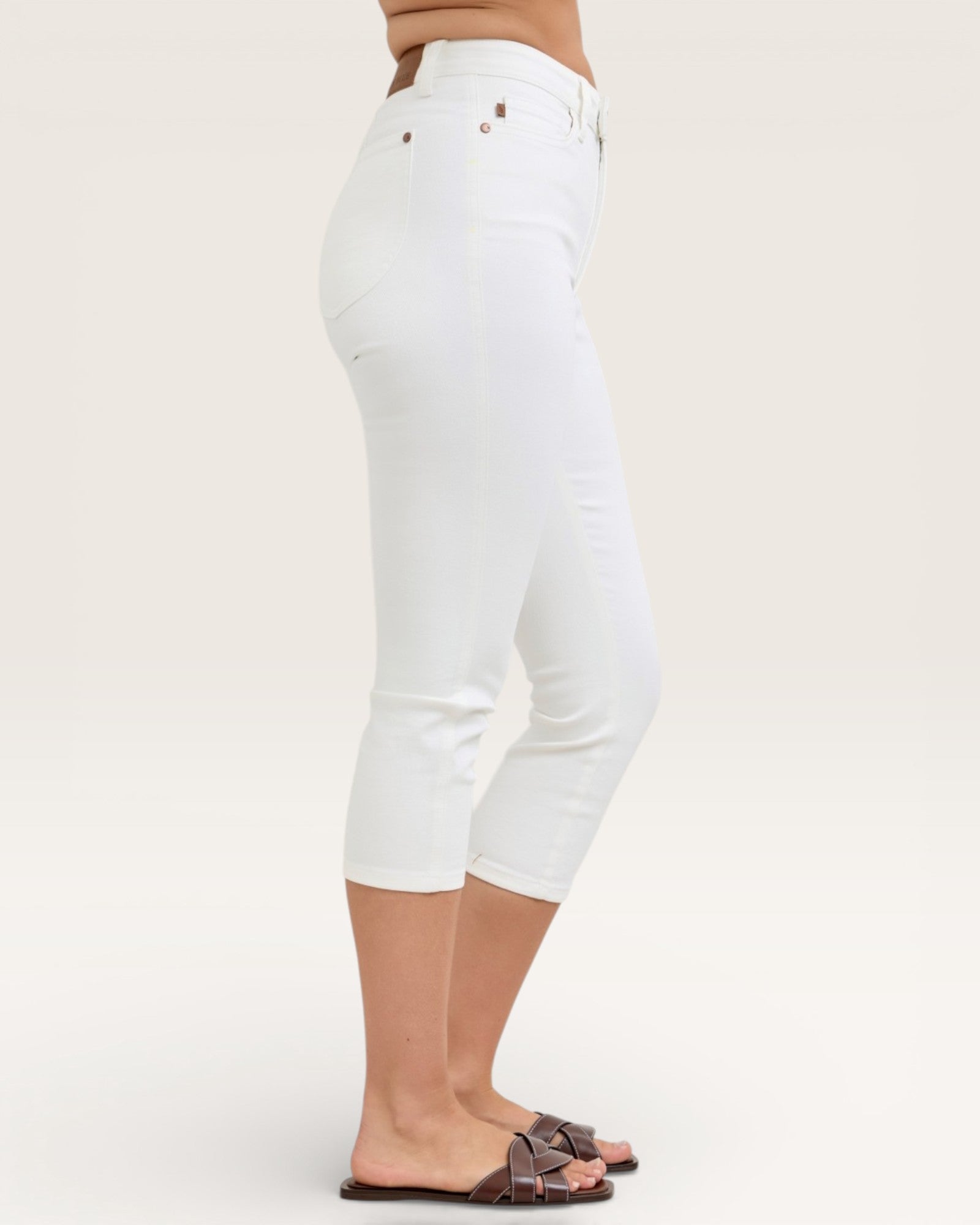 White jeans worn by a person on a plain background