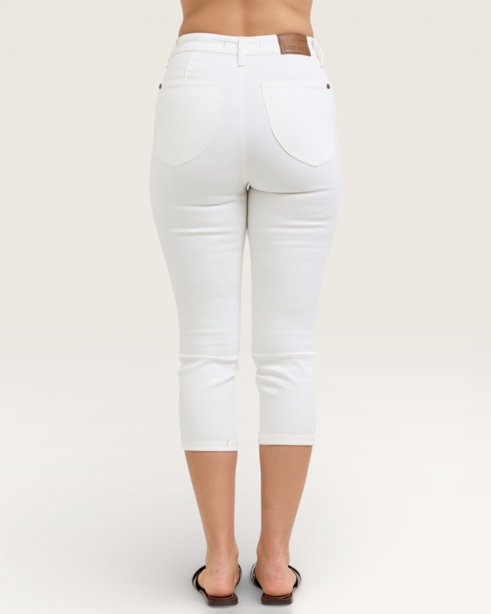 White jeans worn by a person on a plain background