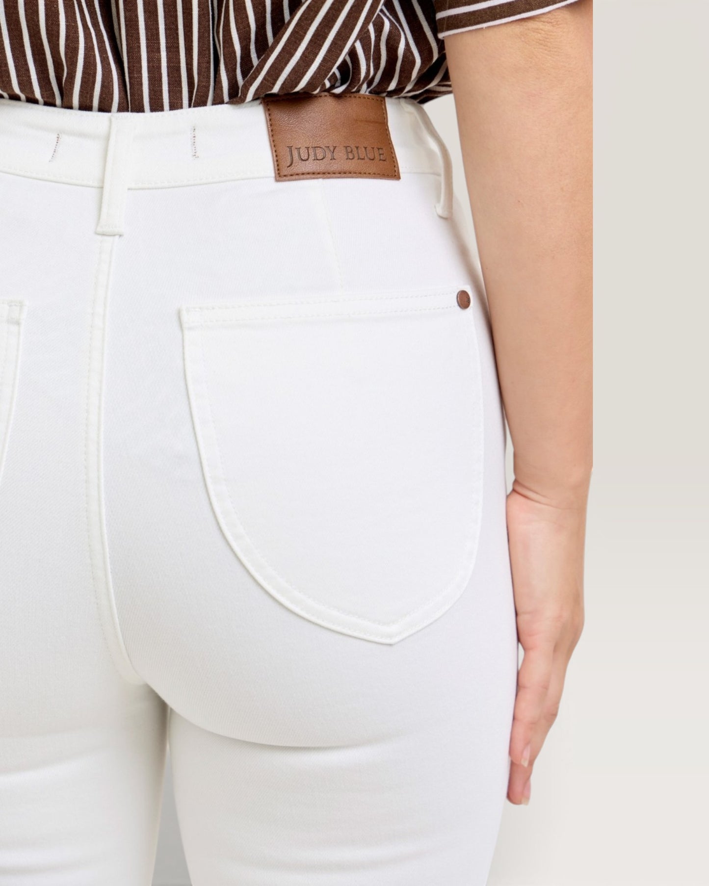 White pants with a brown leather patch displaying 'Judy Blue' brand name.