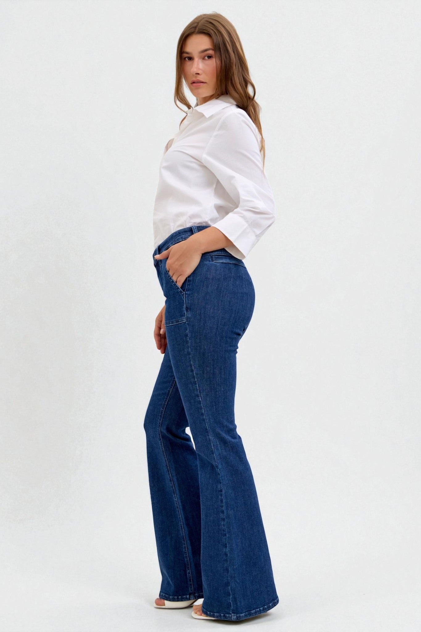 Woman wearing a white blouse and blue flared jeans on a white background