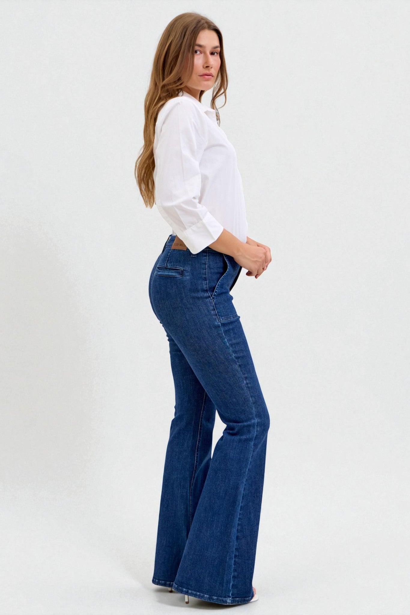 Woman wearing a white shirt and blue flared jeans on a white background