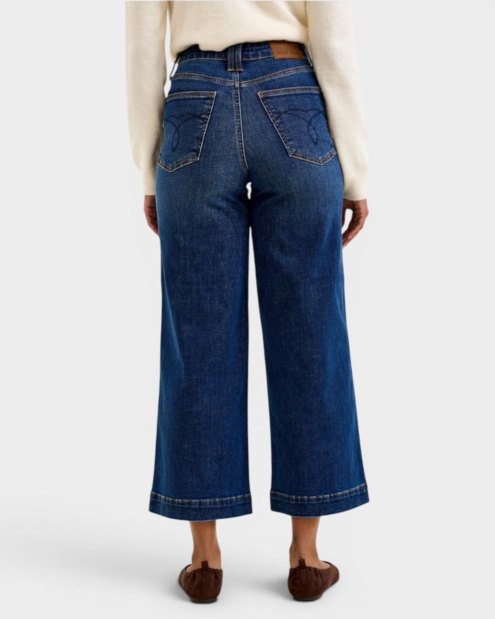 Person wearing blue wide-leg jeans on a white background