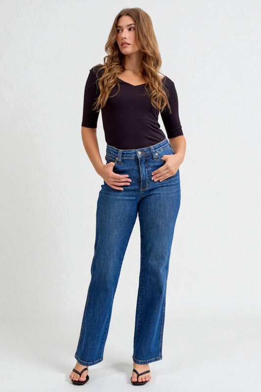 Woman wearing a black top and blue jeans on a white background