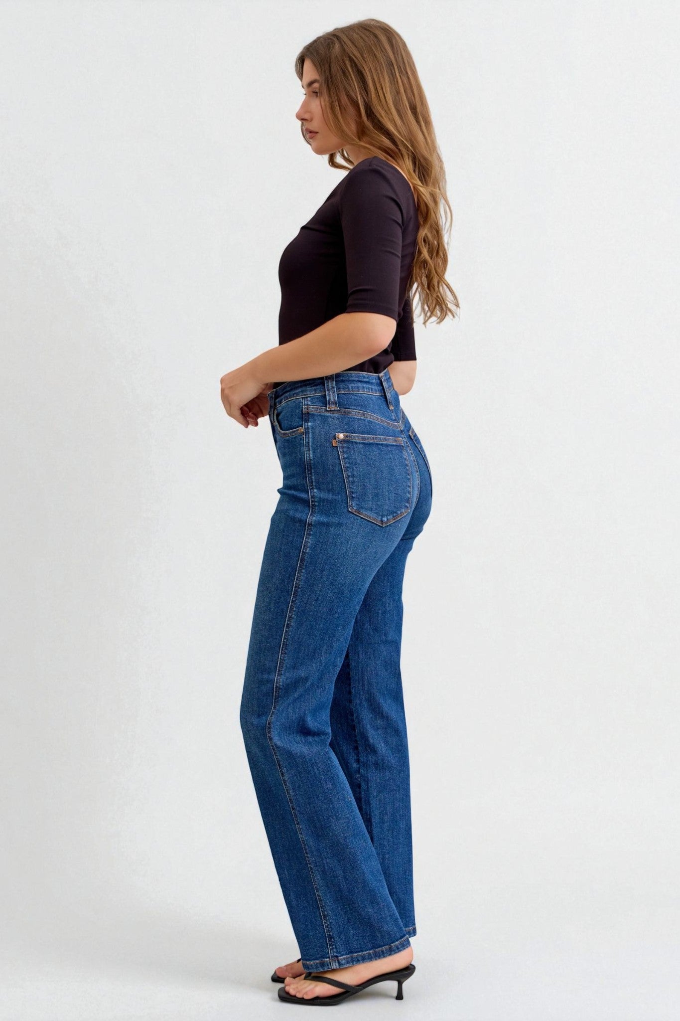 Woman wearing blue jeans and a black top on a white background