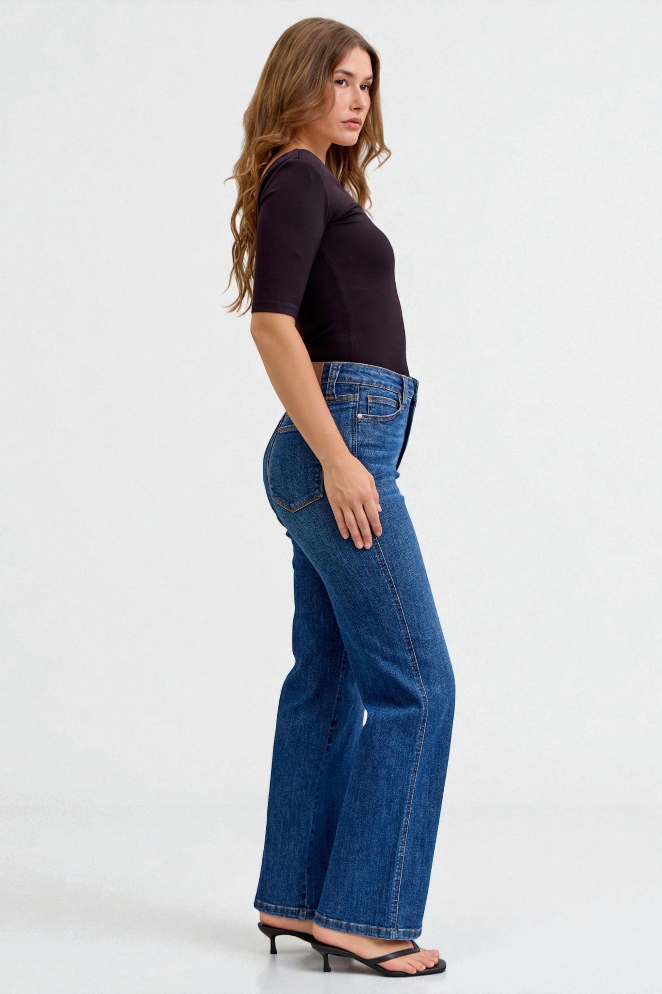 Woman wearing blue jeans and a black top on a white background