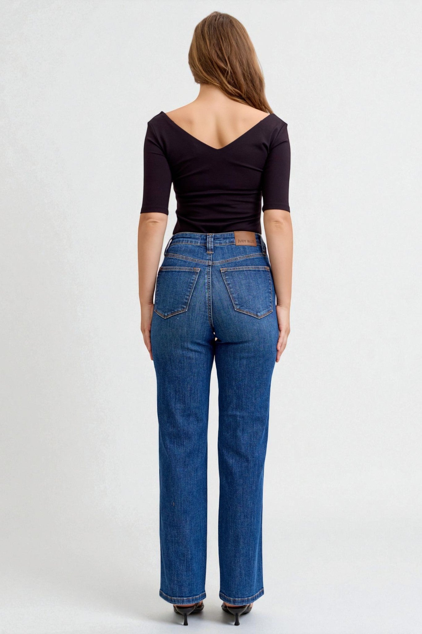 Woman wearing blue jeans and a black top on a white background