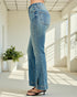 Person wearing blue jeans standing in a bright room with large windows.
