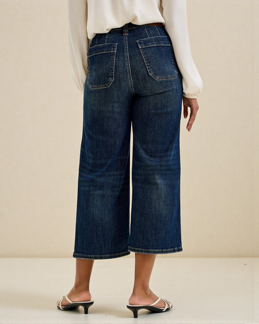 Person wearing dark blue wide-leg jeans on a plain background