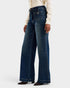 Person wearing dark blue flared jeans on a white background
