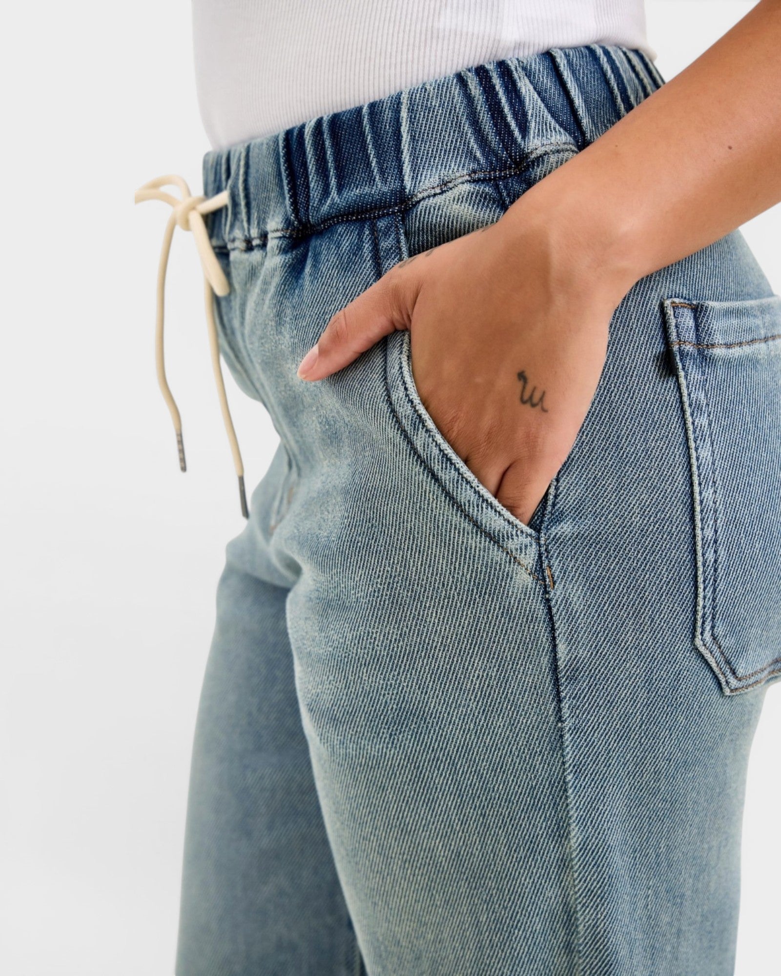 Light blue jeans with a drawstring waist on a white background