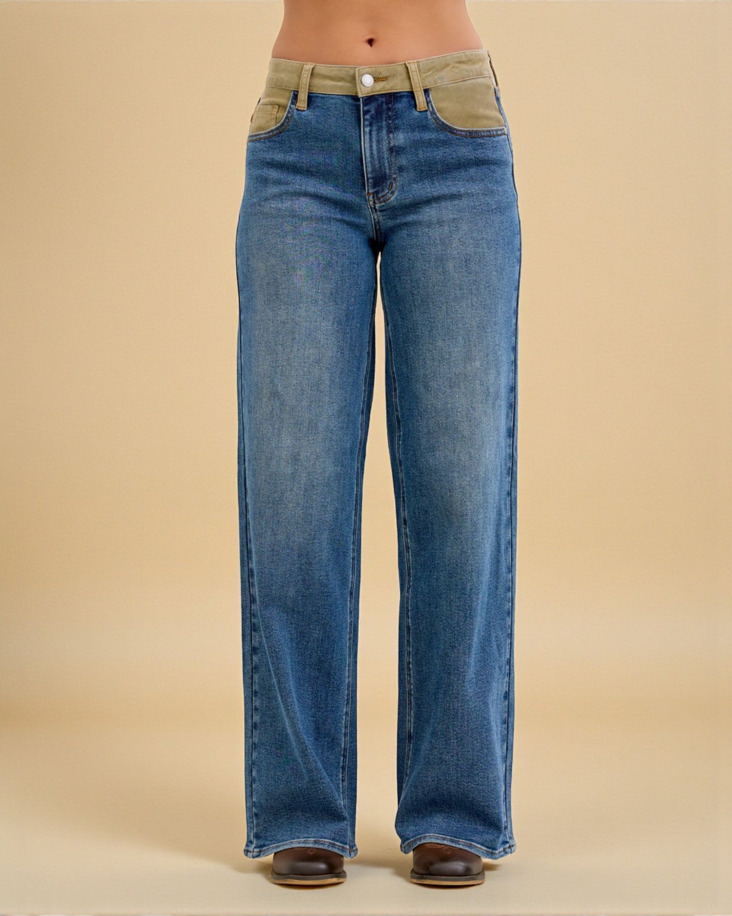 Blue jeans with green patches on a beige background