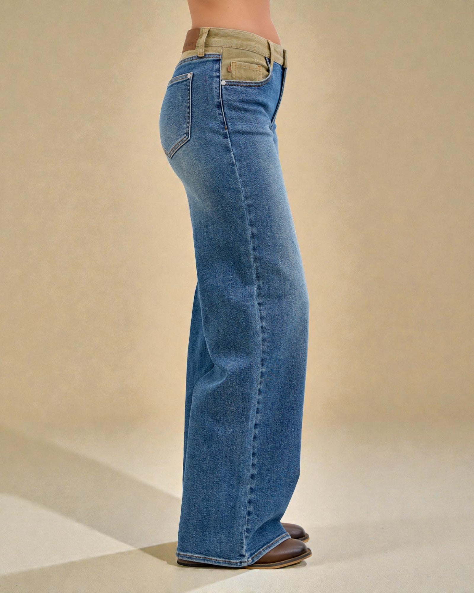 Blue jeans worn by a person on a beige background